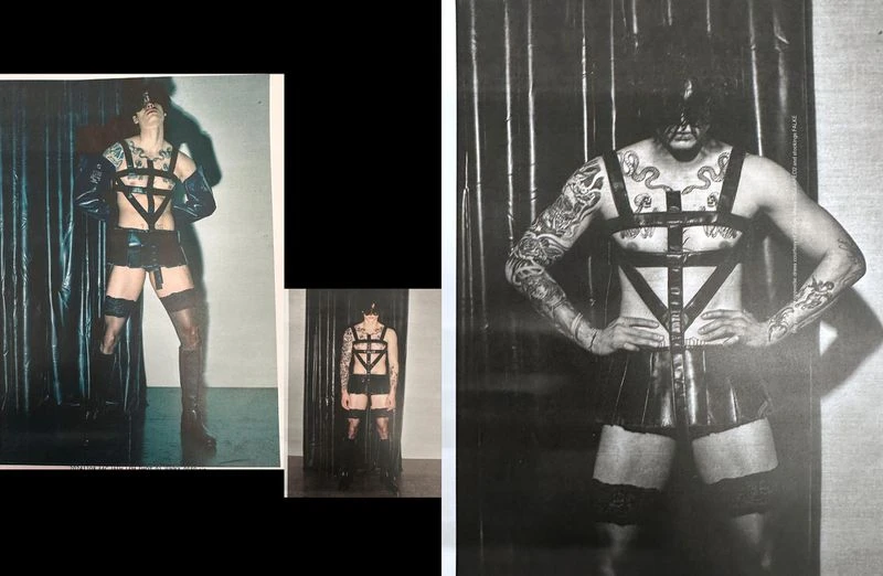 Fashion shot of a tattooed man in a latex harness and briefs, standing in front of a shiny black curtain, bold editorial style.