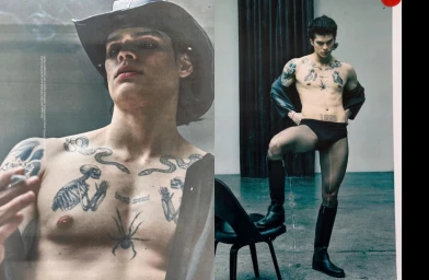 Tattooed man in a cowboy hat and tall boots posing in an editorial spread for The Face Magazine.
