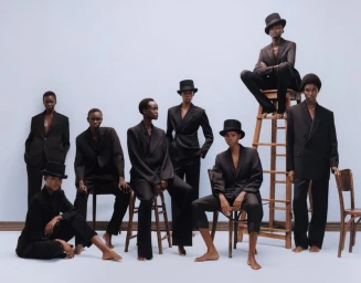 Group of models in black suits and top hats posing against a plain backdrop for American Vogue