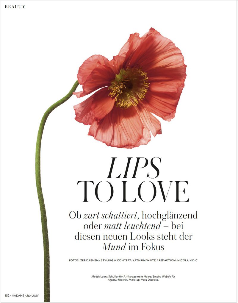 Macro beauty shot of a red poppy flower blossom with a green stem against a white background with beauty magazine text overlay.