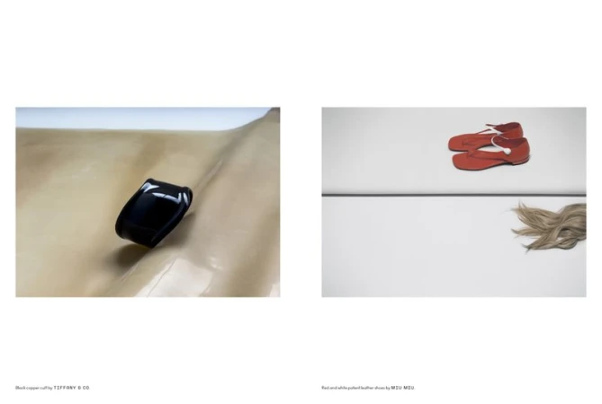 Fashion still life: black cuff bracelet on tan surface, red Mary Jane shoes with white trim, and blond hair on white surface.