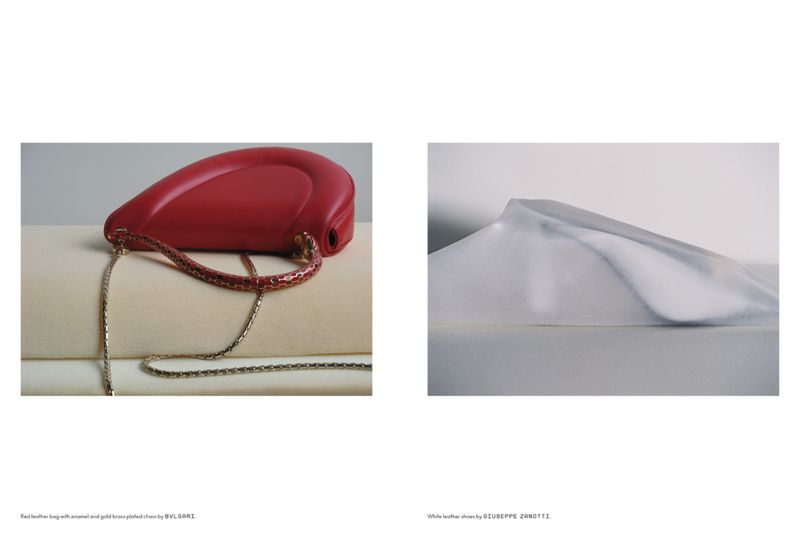 Fashion editorial featuring a red leather BVLGARI purse with a gold chain and a white leather Giuseppe Zanotti shoe on a white background.