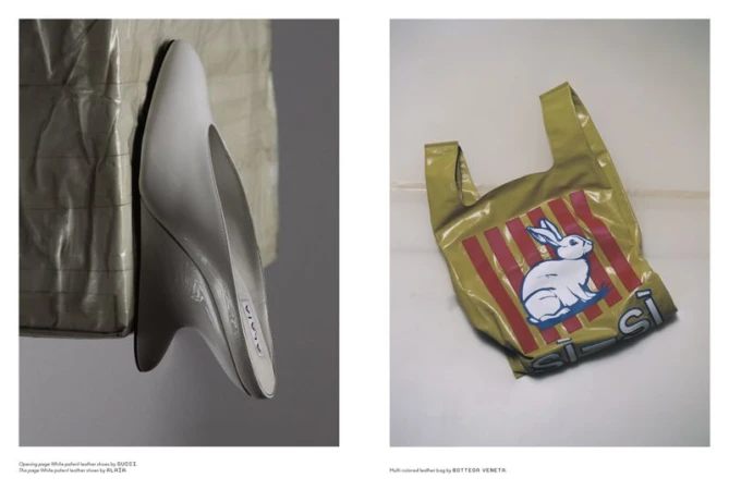 Studio shot of a white sculptural shoe and a plastic shopping bag with a white rabbit print against a white and grey backdrop.