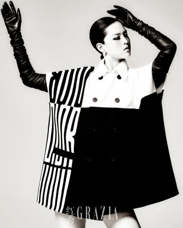Fashion shot of a woman in a color-blocked top and black leather gloves against a neutral background in a studio environment.