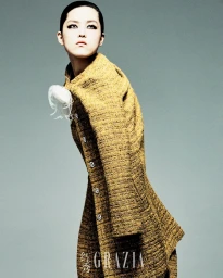 Model Xue Gu wearing a structured mustard tweed coat with white feather detail in Grazia China editorial by Rambo Ding.