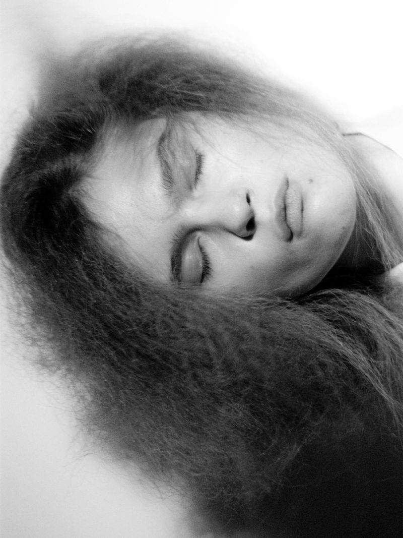 Close-up portrait of a model with textured hair and closed eyes in monochrome