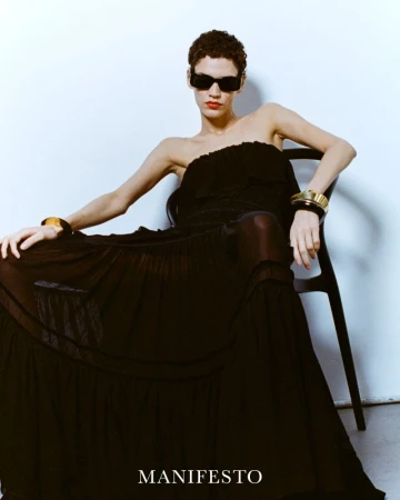 Model Kerolyn Soares wearing a black strapless gown and sunglasses seated on a chair for Manifesto Magazine