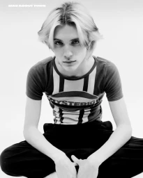 Monochrome portrait of Noen Eubanks wearing a patterned t-shirt and dark trousers against a white seamless background for Man About Town.
