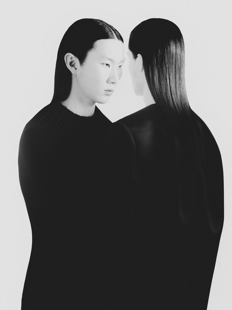 Black and white portrait of an Asian woman with slicked-back hair in front of a second, shadowed woman on a white background.