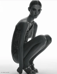 Model Emma Stålhammar crouching in a dark embellished one-piece against a white background for Madame Germany by Zeb Daemen