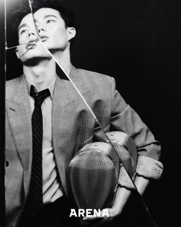 Black and white portrait of a stylish adult male wearing a blazer and tie, with a broken glass pane and 'ARENA' text overlay.
