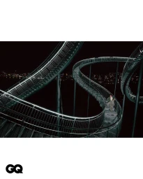 Model standing on a massive illuminated twisting metal staircase at night for GQ Korea