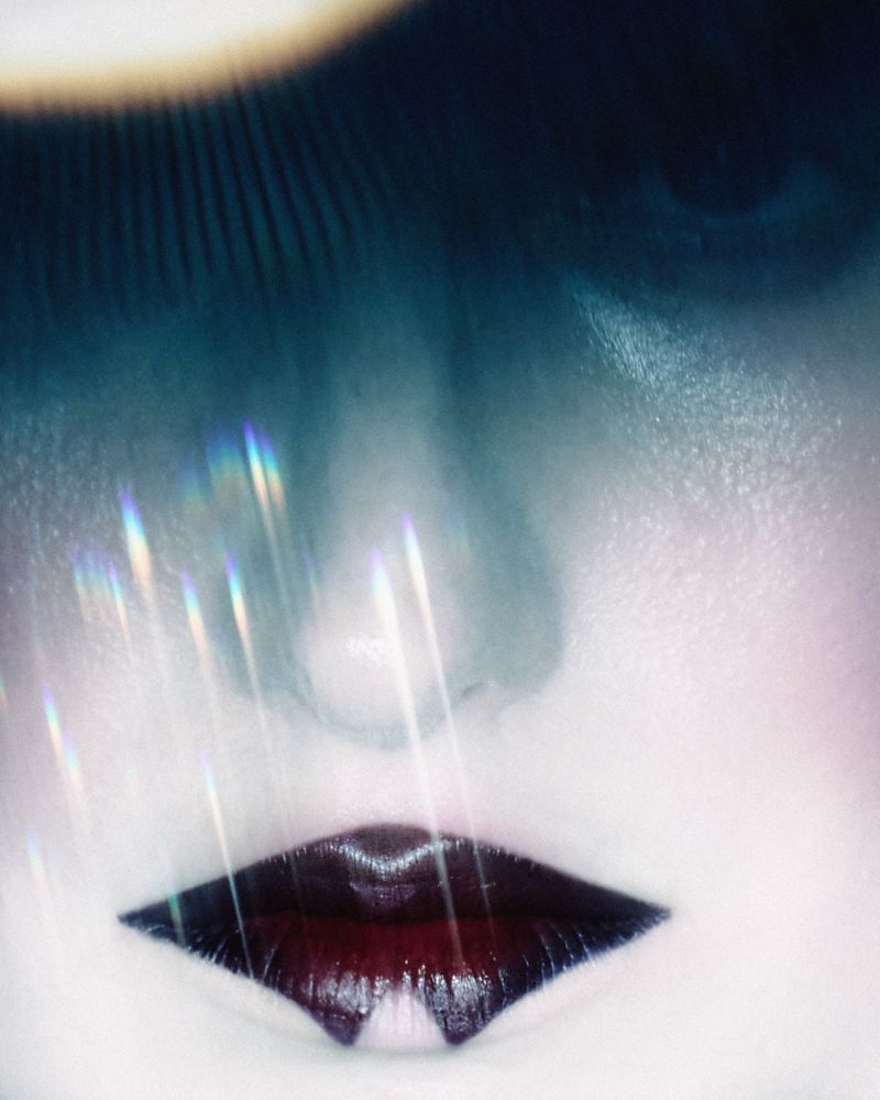 Close-up portrait of a person with dark lips and ethereal light flares across the face for Numéro Switzerland editorial