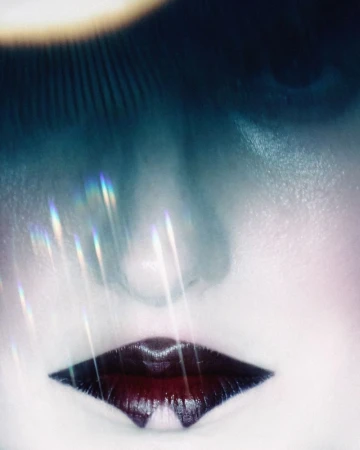 Close-up portrait of a person with dark lips and ethereal light flares across the face for Numéro Switzerland editorial
