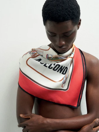 Model wearing a printed silk scarf with red and white sections against a clean white background