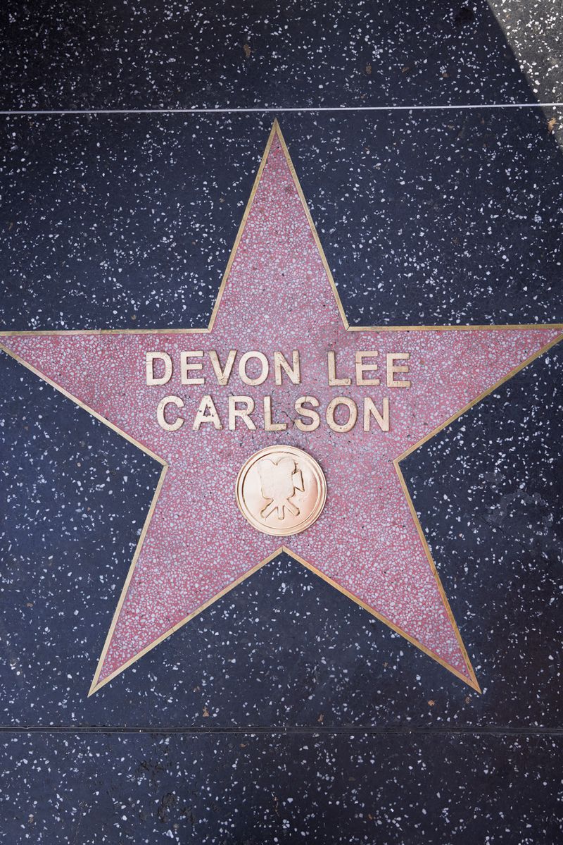 Close-up of Devon Lee Carlson's star on the Hollywood Walk of Fame. Star-shaped plaque inlaid in dark speckled concrete, with text.