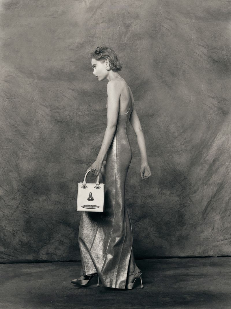 A woman in a shimmering gown holds a unique handbag in a studio setting, showcasing a blend of fashion and photographic art.