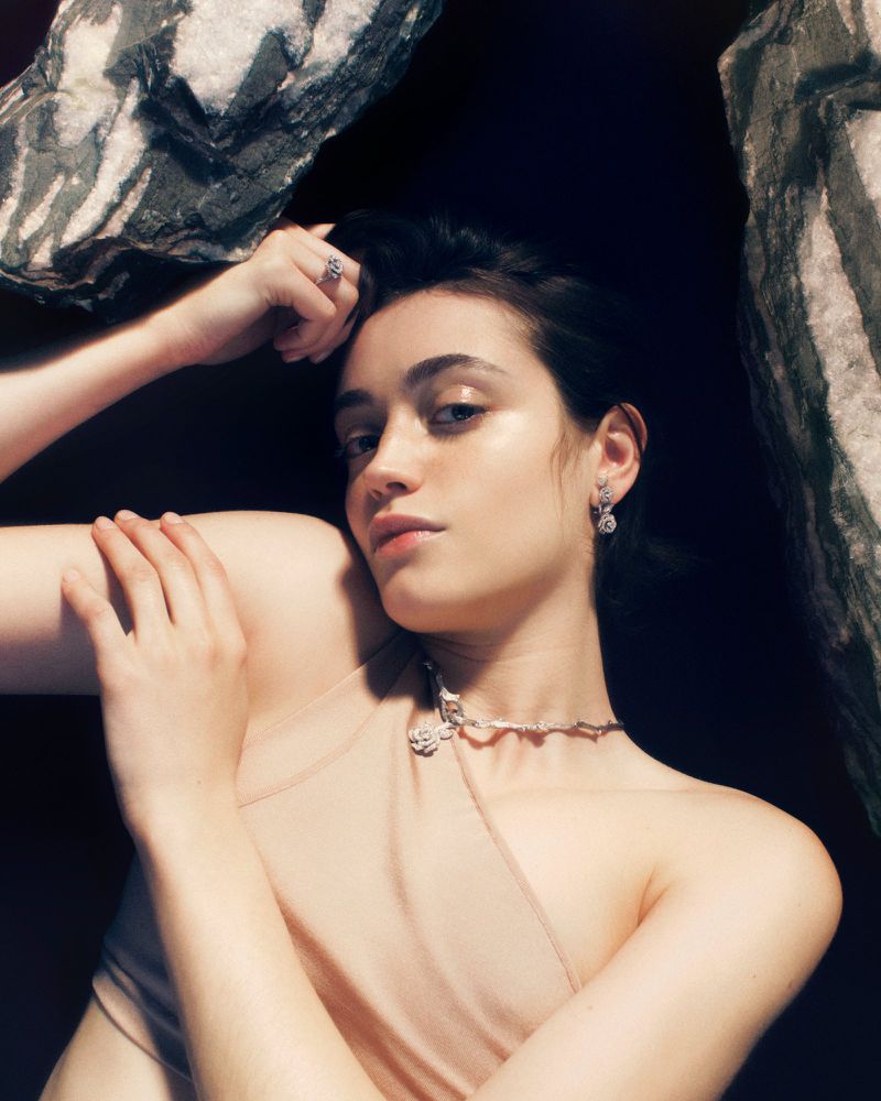 Model Kim Schell wearing high jewelry necklace and ring framed by textured rock formations for Vogue Polska