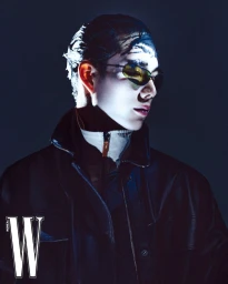 Model wearing dark sunglasses and black jacket against a dark background for W Korea editorial shoot