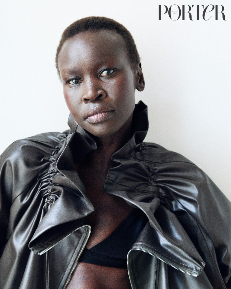 Close-up shot of an African-descent adult female model wearing a black jacket against a white background for a fashion editorial.