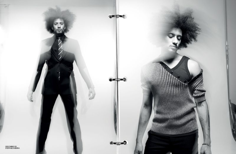 Black and white studio fashion shot of a man with an afro in a suit next to a man with an afro in a sweater.