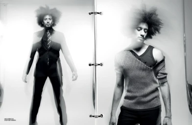 Black and white editorial portrait featuring a man with a large afro wearing a black suit and patterned tie, shot with multiple exposure.