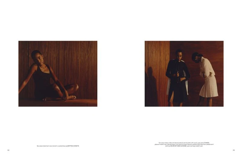 Editorial fashion shot with two African-descent women in a brown wood-paneled setting, one in a dark dress and the other in a light-colored suit.