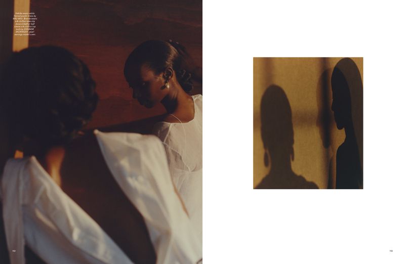 Two Black women in light dresses are highlighted in soft, diffused lighting next to an abstract image of their shadows on a wall.