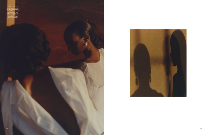 Two Black women in light dresses are highlighted in soft, diffused lighting next to an abstract image of their shadows on a wall.
