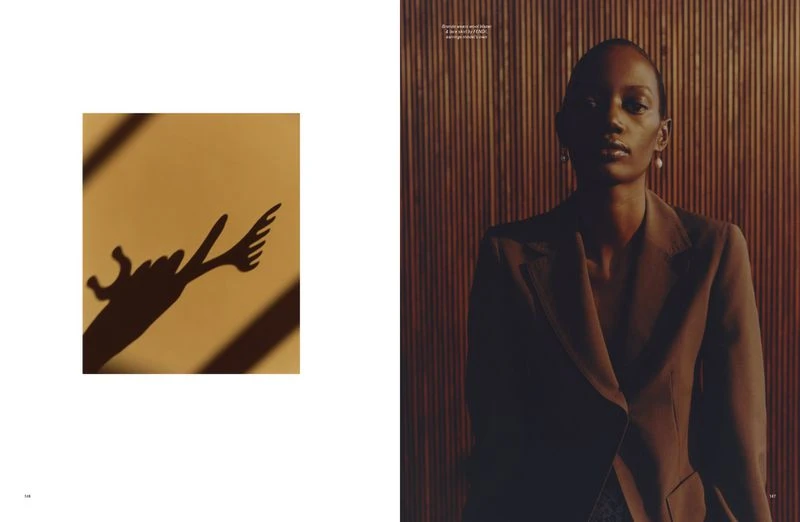 Fashion editorial shot of a slender adult woman in a brown blazer against a wood-paneled wall, contrasted with a shadow-puppet image.