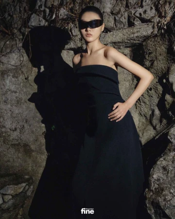 Model in a black strapless dress and futuristic sunglasses posing against a rugged rock wall for Esquire China