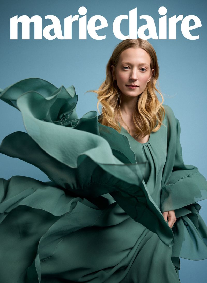 Fashion editorial shot of a blonde woman in a flowing green gown with a blue background and Marie Claire magazine text overlay.