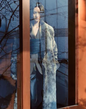 Model seen through glass reflection wearing a textured grey coat for Marie Claire Korea editorial