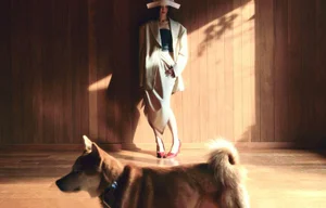 Model in cream blazer and skirt standing against wood paneled wall with dog in foreground for Marie Claire Korea