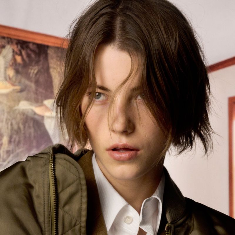 Close-up portrait of a model with short brown hair wearing an olive green jacket and white collared shirt for The Face Magazine.
