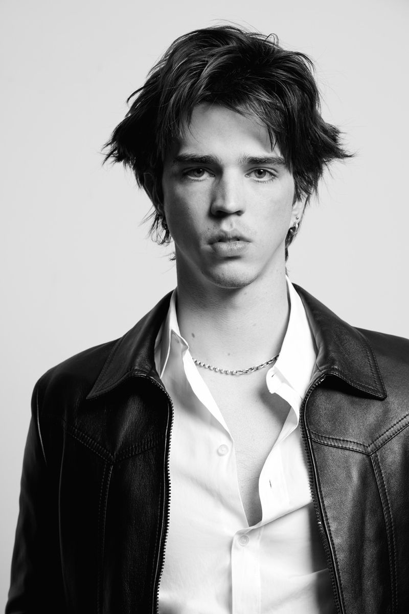Portrait of actor Seth Lee wearing a leather jacket and white shirt against a white seamless background for HERO Magazine.