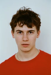 Portrait of actor Sam Nivola wearing a red t-shirt against a plain light background for HERO Magazine.