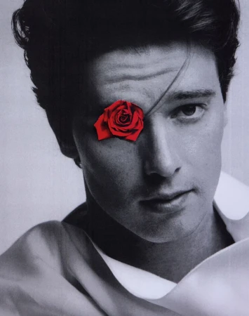 Portrait of Patrick Schwarzenegger in monochrome with a vibrant red rose collage covering one eye for HERO Magazine.