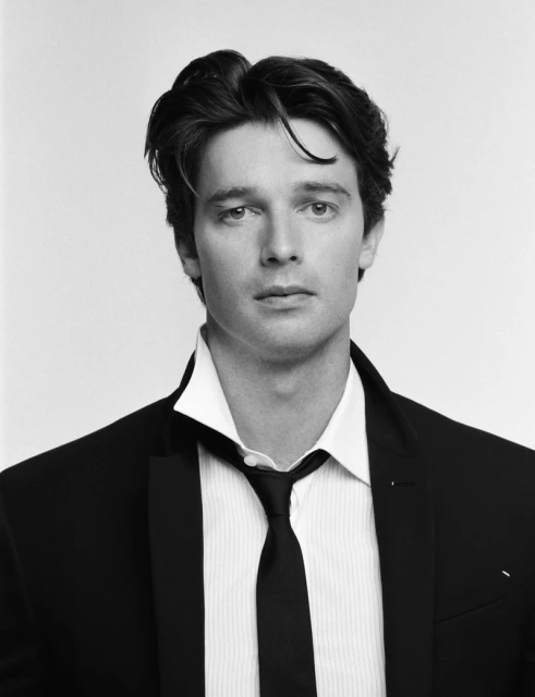 Black-and-white portrait of an adult male in a suit, white shirt, and tie against a clean, bright backdrop in a close-up studio shot.