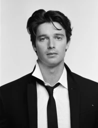 Monochrome portrait of actor Patrick Schwarzenegger in a dark suit and white shirt for HERO Magazine