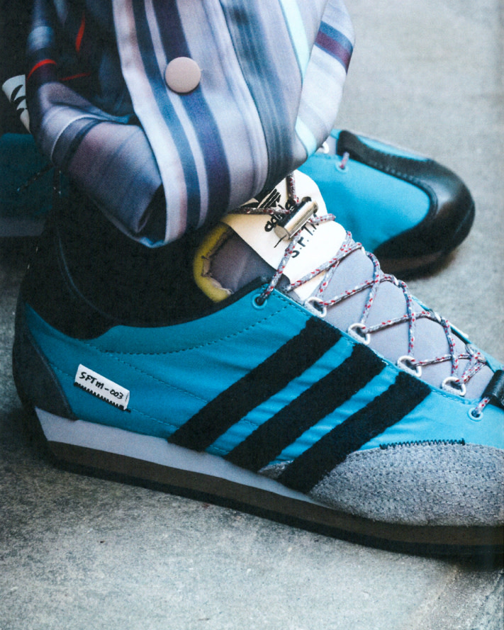 Close-up of blue and black Adidas running shoes with striped silk pants. The focus is on the details and textures of the footwear.