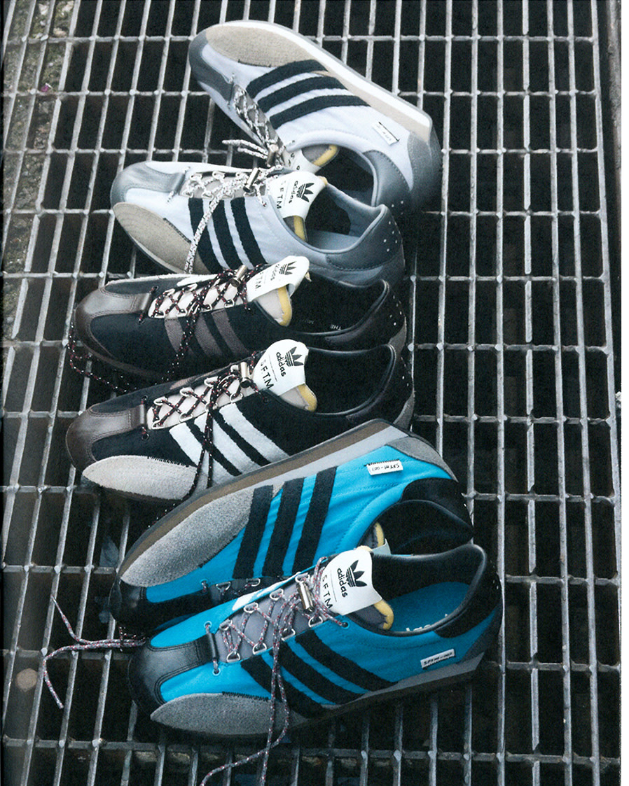 A collection of Adidas sneakers in blue, black, white, and grey colors are artfully arranged on a textured metal grate.