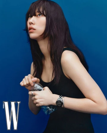 Portrait of an East Asian woman with dark hair and black tank top holding a water bottle against a royal blue backdrop for W Korea.