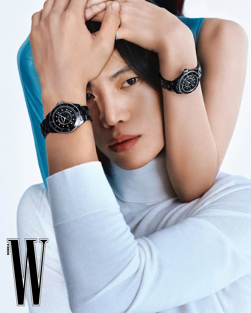 Portrait of an adult male with a female's arms around his neck, both wearing black watches in a white studio setting.