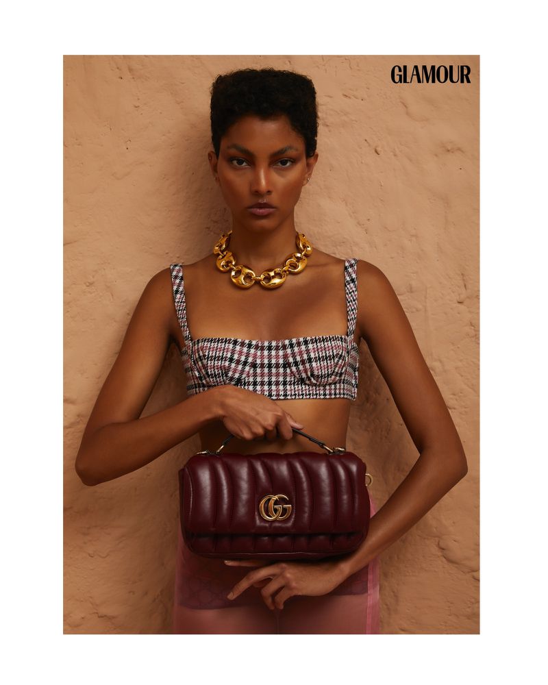 Glamour editorial fashion shot: a model poses with a Gucci handbag against a beige background, showcasing a stylish and sophisticated aesthetic.