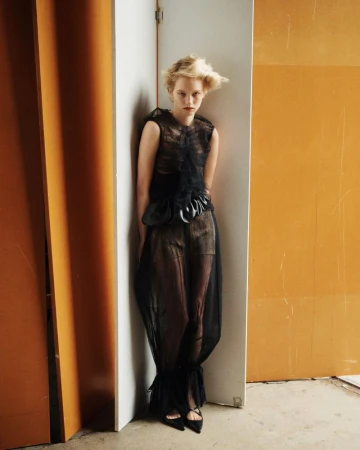 Model in a black sheer dress standing between wooden panels for SSAW Magazine