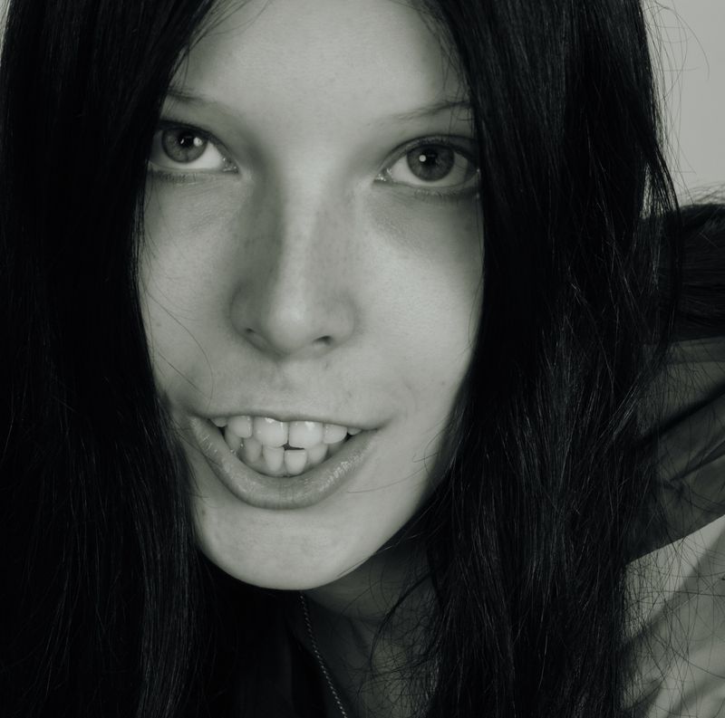Close-up portrait of a young woman with long dark hair smiling against a plain white background for PUBLIC Editions Touch Grass.