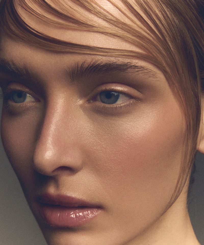 Close-up portrait of a woman with sleek wet hair strands on her forehead and natural glossy makeup