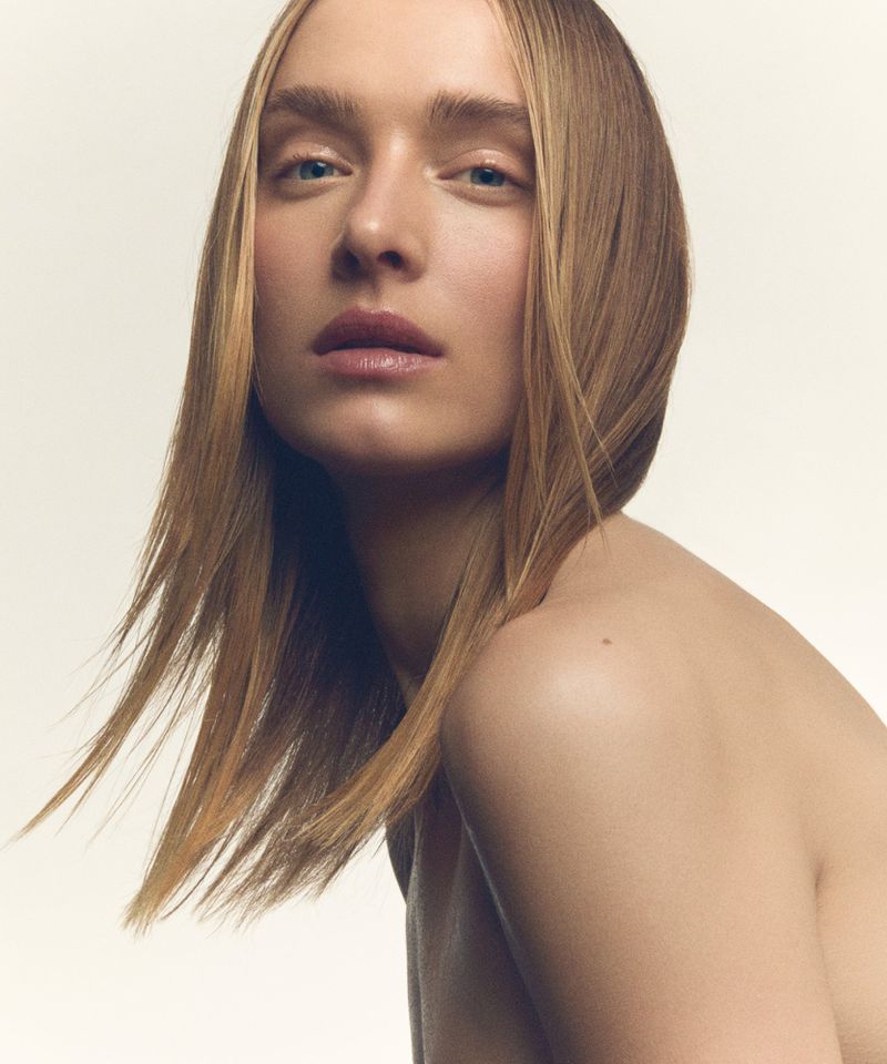 Close-up beauty portrait of a model with long blonde hair against a plain white background for SCMP Style.