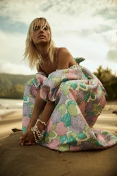 Model crouching on a sandy beach wearing a floral print dress for Alemais Trippy Troppo campaign shot by Georges Antoni